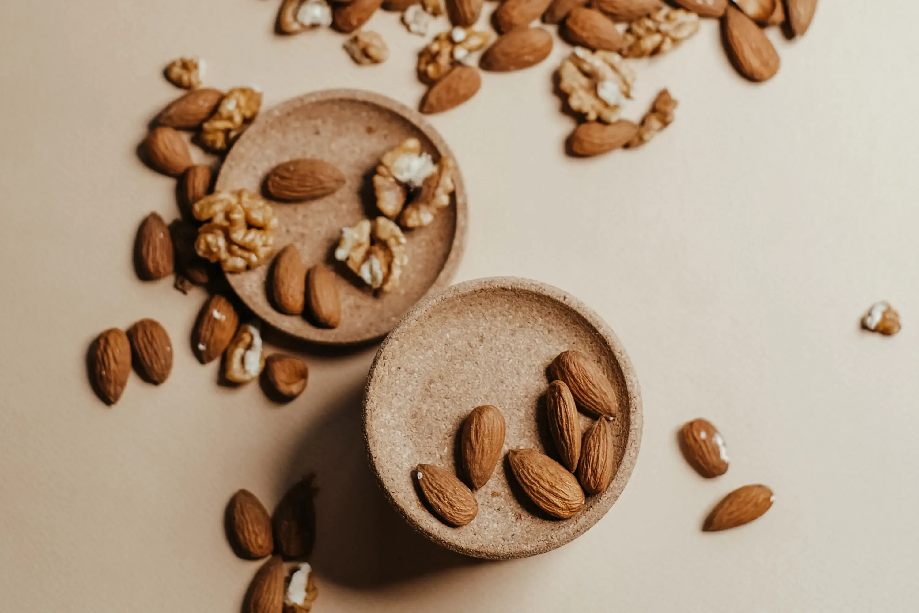 almonds and walnuts scattered on a tan countertop